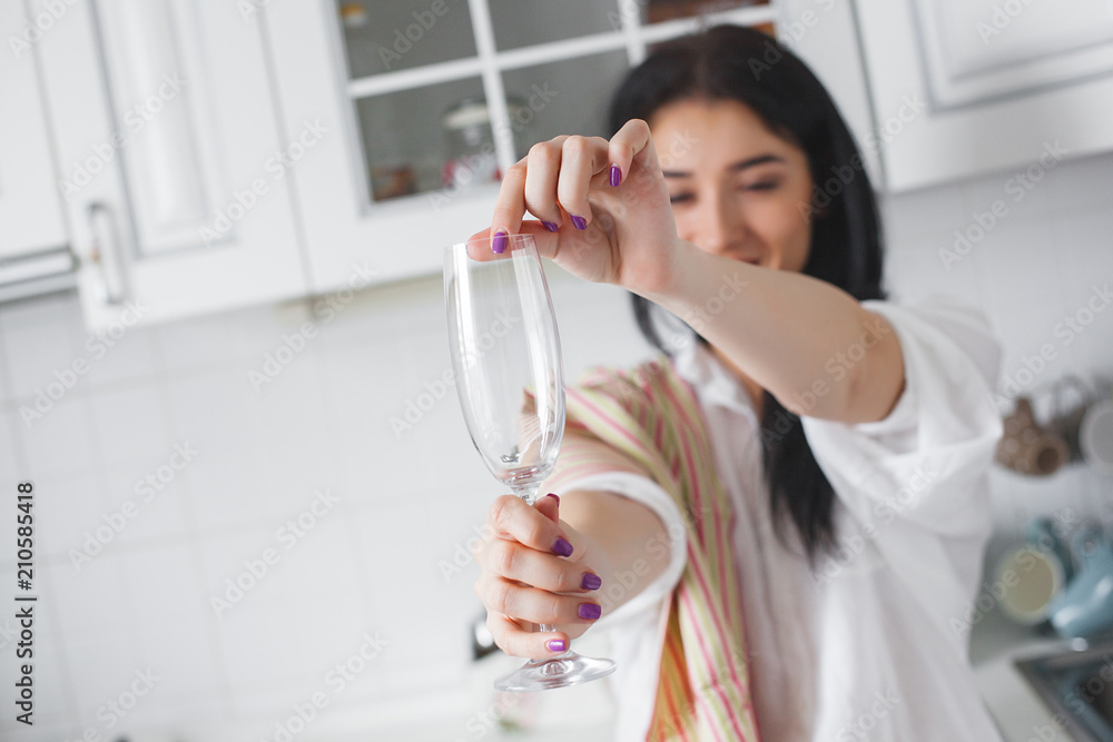 Young attractive woman washing a glass at the kitchen. Housewife washing a dish indoors Young attractive woman washing a glass at the kitchen. Housewife washing a dish indoors