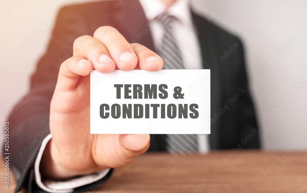 Businessman holding a card with text Terms And Conditions Businessman holding a card with text Terms And Conditions