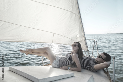 Romantic couple in love on sail boat at sunset under sunlight 