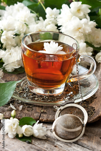 Composition cup of tea and jasmine flowers on wooden background