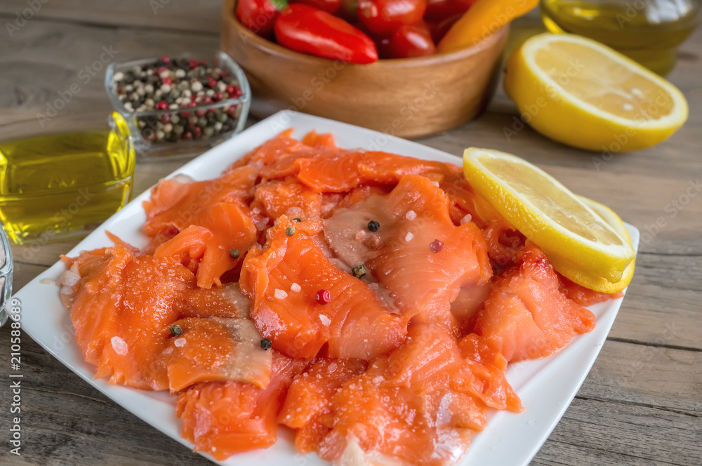 Raw pickled trout fillet and salmon pieces in a white plate. Wooden background. Raw pickled trout fillet and salmon pieces in a white plate. Wooden background.