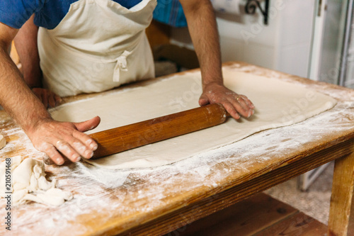 Baker kneading dough in a bakery. Traditional Bakery Concept.