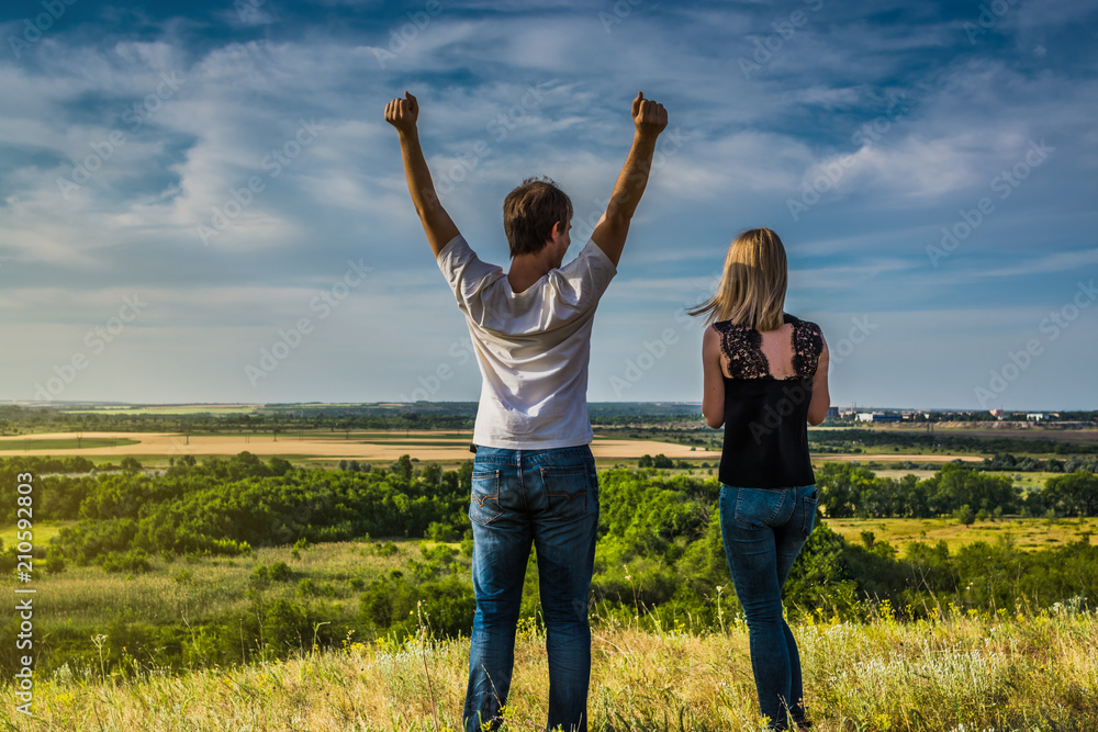 Happy couple with open arms on the field under the cloudy sky Happy couple with open arms on the field under the cloudy sky