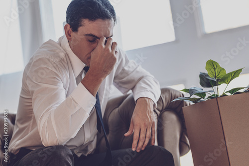 Being fired. Unhappy jobless man sitting at home while not knowing what to do