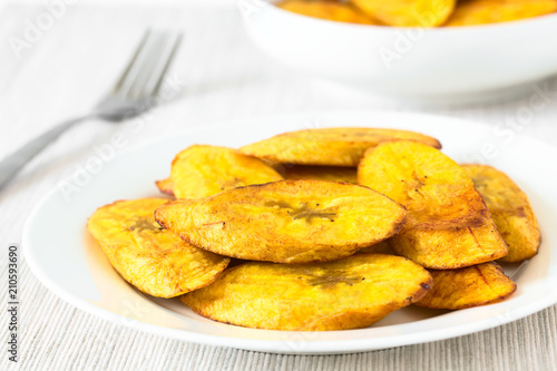 Fried slices of ripe plantains traditional snack and accompaniment in Latin America, photographed with natural light (Selective Focus on the front of the top slice)