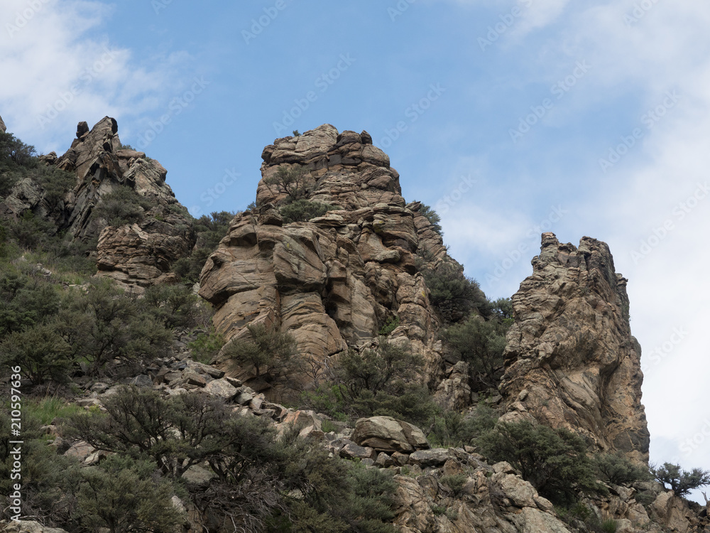 Outcropping of Ancient Metamorphic Rock in Montana with blue sky and thin clouds overhead. Photographed from below.