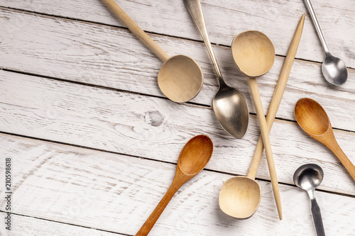 rom above of wooden, metal spoons of varied shapes lying on white wooden background