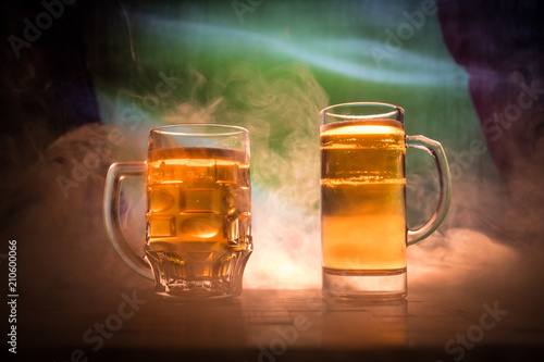Creative concept. Beer glasses on table at dark toned foggy background with blurred view of flag of Belgium. Support your country with beer concept.