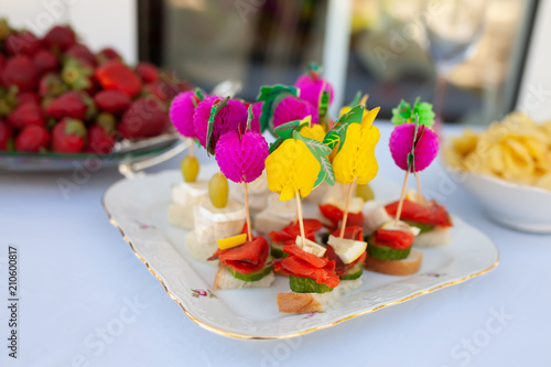 Cold appetizers, canape with red fish, cucumber and lemon served on the plate, catering, close up
