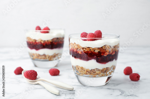 Delicious oatmeal dessert with raspberries in glasses on table