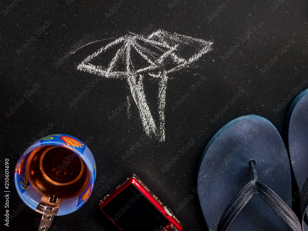overhead drawn umbrella summer concept on black chalkboard with travel accessories