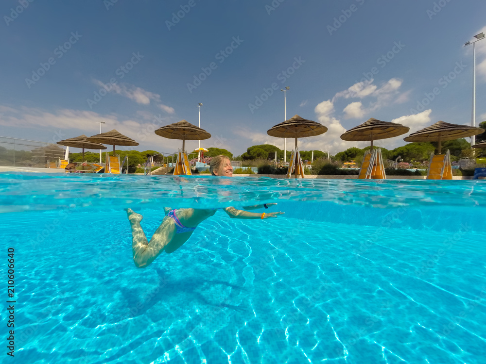 Fototapeta premium Young woman swimming undewater in the swimming pool
