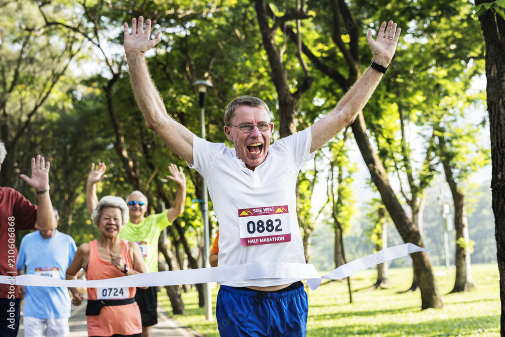 Obraz premium Happy senior running through the finish line