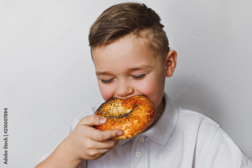 Little boy eating a bagel with poppy seeds. Little boy eating a bagel with poppy seeds.