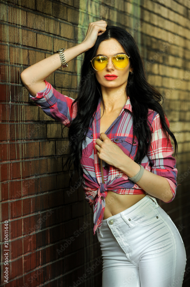 Fototapeta premium Gorgeous young model woman with perfect figure wearing trendy outfit posing in the city street.