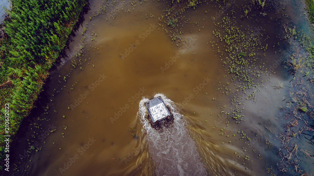 Obraz premium An off-road vehicle sails on the river. aerial above view top