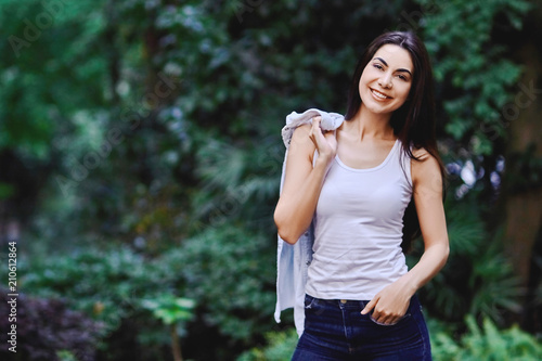 Happy young girl holding shirt in her hands in sleeveless t-shirt