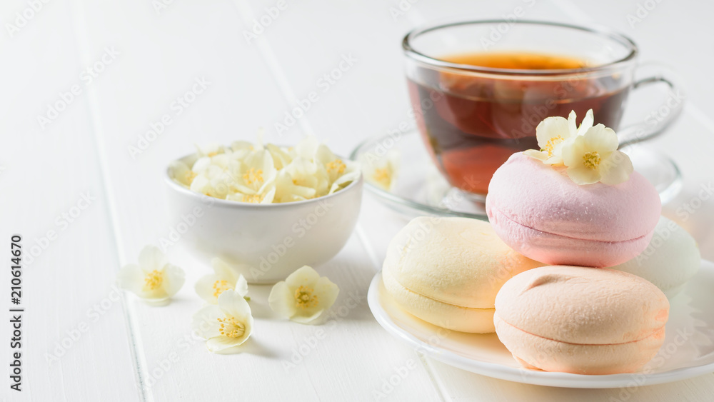Herbal tea, a bowl of marshmallows and jasmine flowers on a rustic table. The composition of the morning Breakfast. Herbal tea, a bowl of marshmallows and jasmine flowers on a rustic table. The composition of the morning Breakfast.