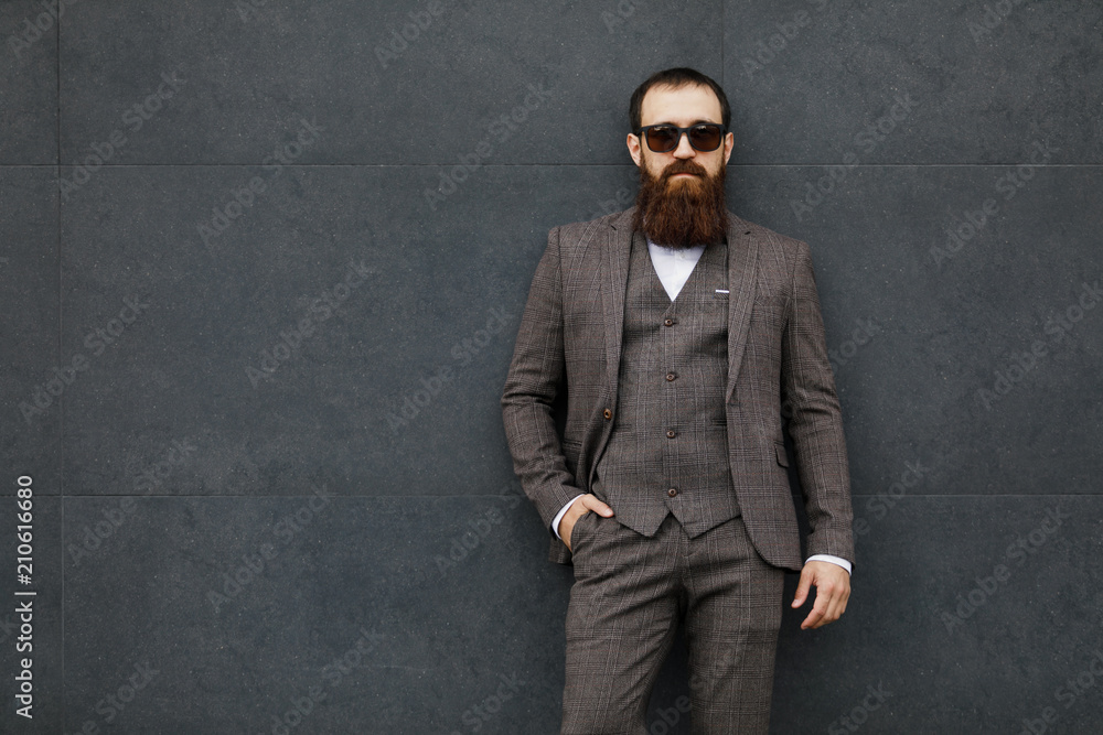bearded man in sunglasses with a very interesting look with cityscape in the background
