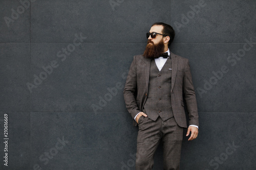 bearded man in sunglasses with a very interesting look with cityscape in the background