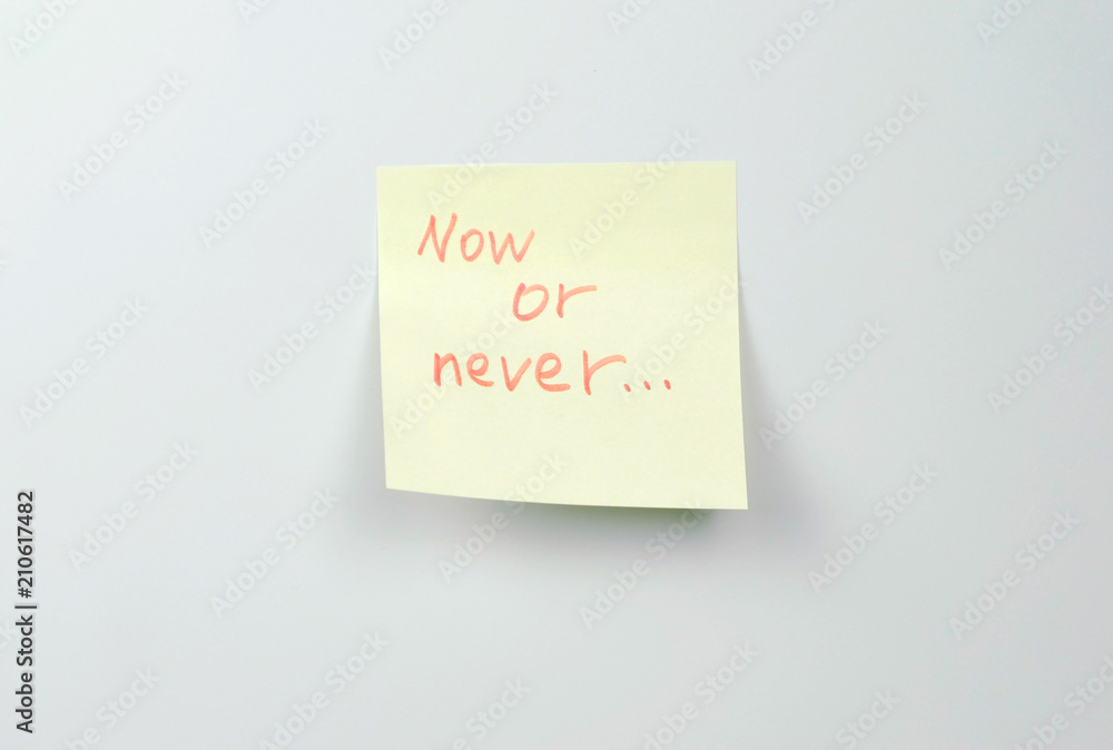 Note on yellow sticker paper sheets with motivation words now or never.