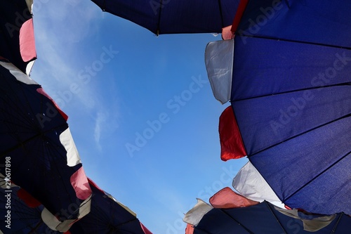 Looking up at a violet parasol with blue sky background  big umbrellas at the beach.