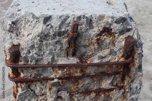 Old reinforced concrete pillar with rusty armature on the seashore close-up.