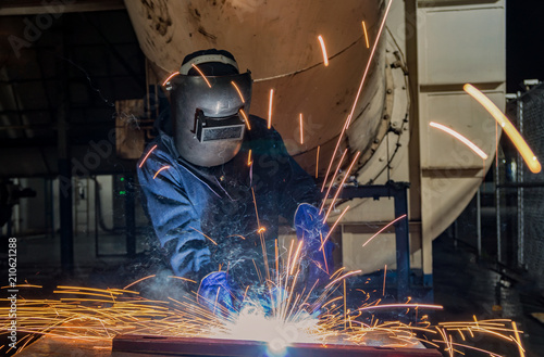 Industrial worker is welding repair steel part in factory