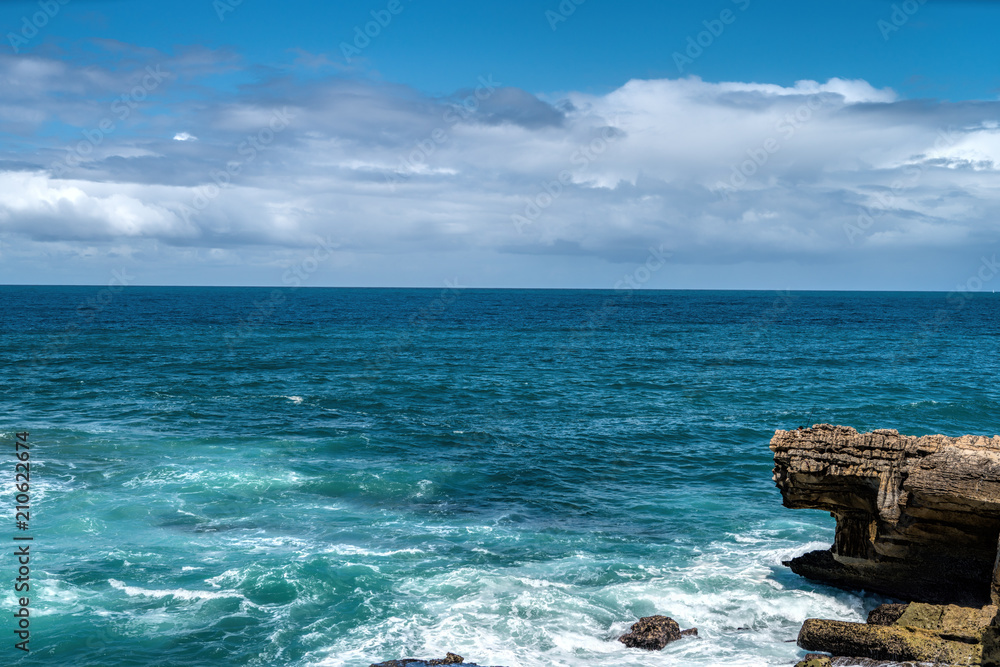 Waves are beating against rocky shore of sea on sunny summer day