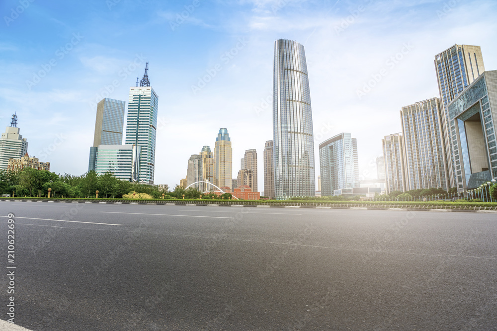 The empty asphalt road is built along modern commercial buildings in China's cities.