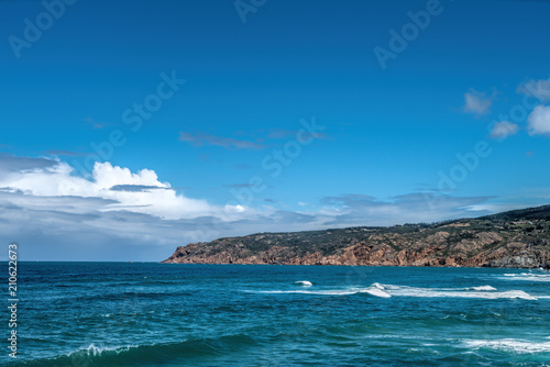 Waves are beating against rocky shore of sea on sunny summer day