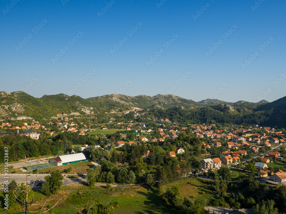 Panorama of Cetinje town, Montenegro, ancient mountain city with pretty little houses, ginger roofs and forest around Panorama of Cetinje town, Montenegro, ancient mountain city with pretty little houses, ginger roofs and forest around