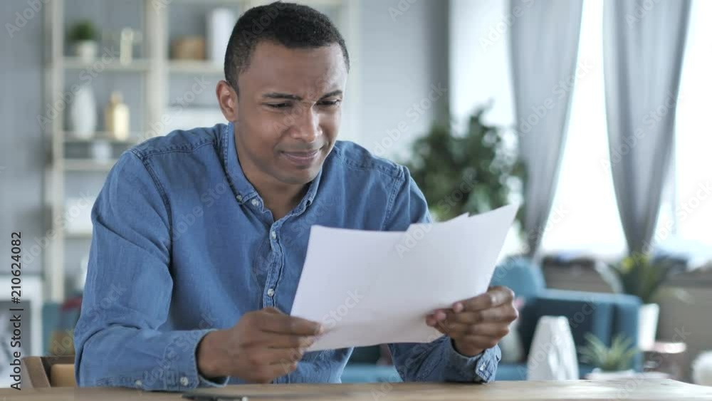Young African Man Upset after Reading Documents, Feeling Sad Young African Man Upset after Reading Documents, Feeling Sad