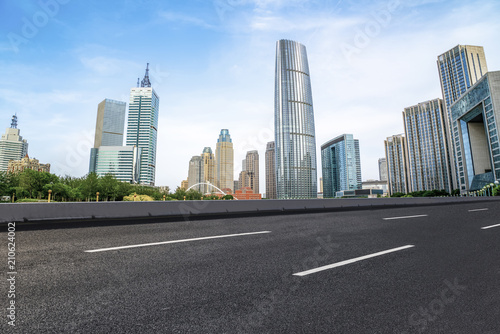 The empty asphalt road is built along modern commercial buildings in China s cities.