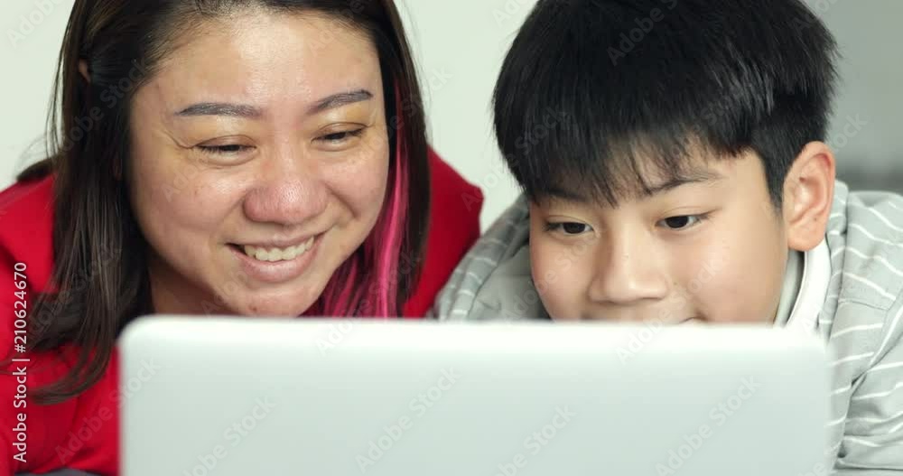 Happy young mother and son watching on laptop computer . Then they looking through the screen with smile face Happy young mother and son watching on laptop computer . Then they looking through the screen with smile face