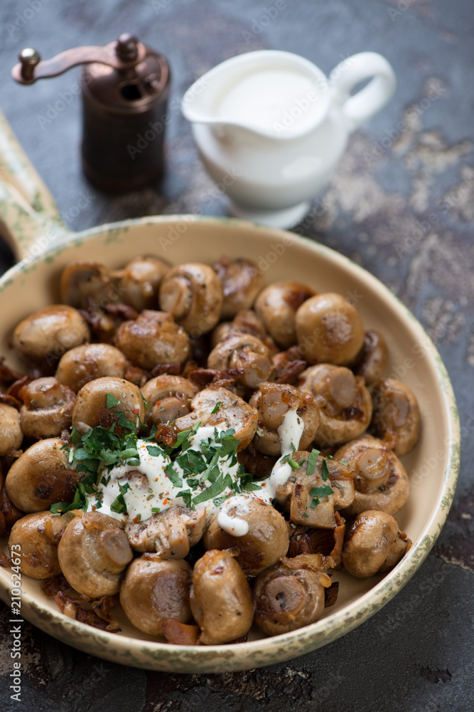 Closeup of roasted champignons and chanterelles with sour cream and parsley in a serving pan, studio shot Closeup of roasted champignons and chanterelles with sour cream and parsley in a serving pan, studio shot
