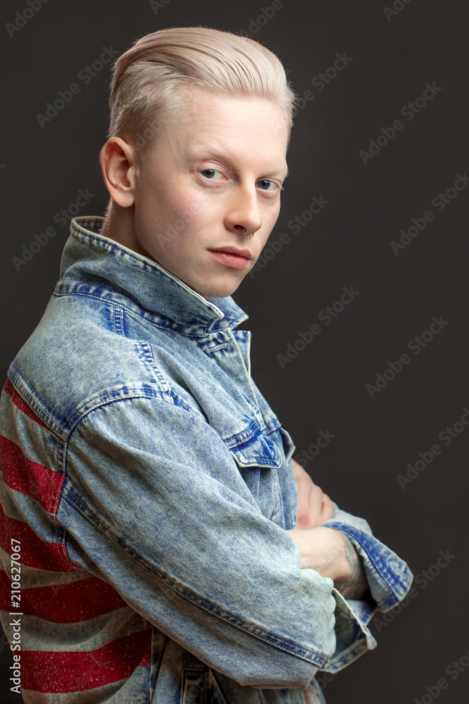 Cute albino male model with perfect skin and hairstyle wearing jeans jacket  looking at camera posing with crossed hands over black background with copy  space. Stock Photo | Adobe Stock