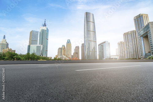 The empty asphalt road is built along modern commercial buildings in China s cities.