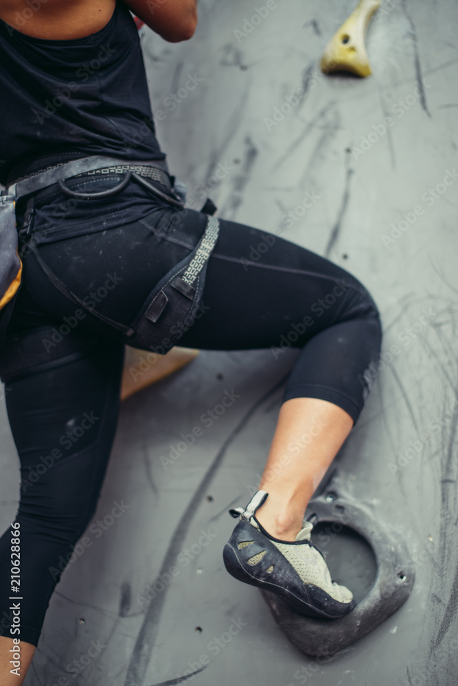 Bottom close up view of rock climber female feet on artificial climbing wall. Woman feet in
