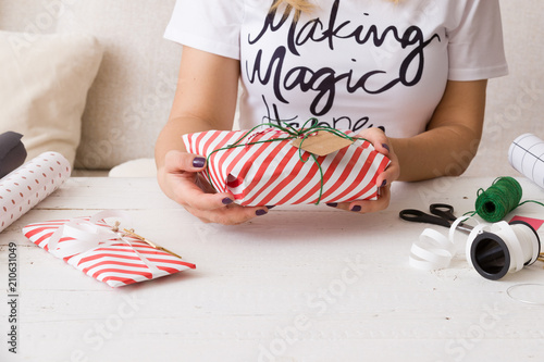 Closeup of girl's hands wrapping Christmas of birthday gifts and decorating then with ribbons and tags. Holiday season