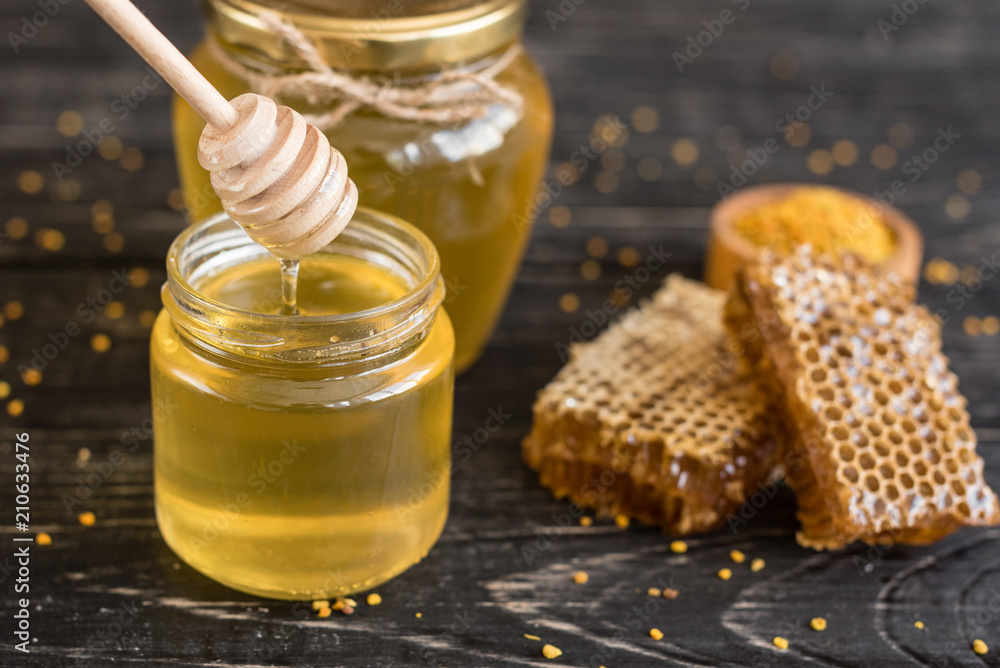 Beautiful transparent honey in bank, honeycombs and pollen on a wooden table. It can be used as a background Beautiful transparent honey in bank, honeycombs and pollen on a wooden table. It can be used as a background