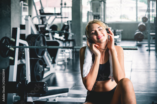 woman listening to music during workout and take a rest at sport gym for relaxation with happy and smile