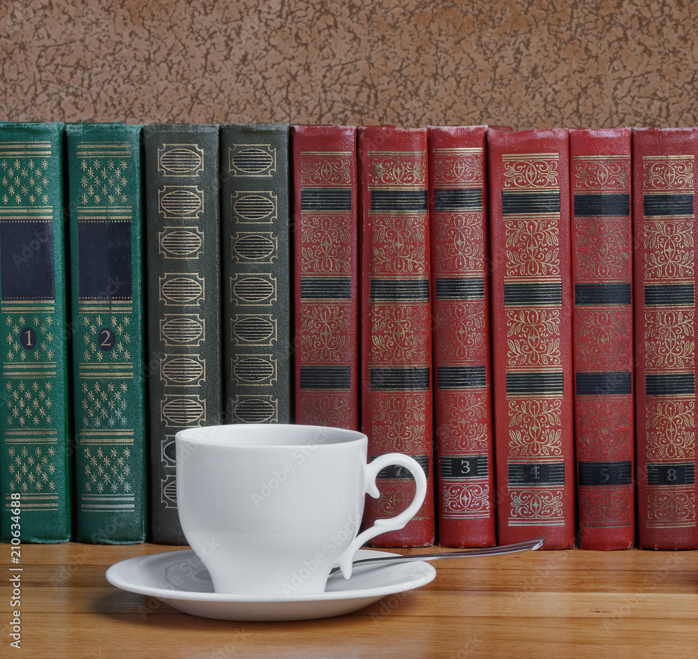 Naklejka premium Hot cup of fresh coffee on the wooden table with books