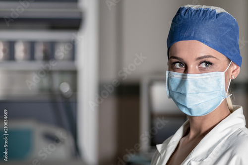 Young blonde nurse in ER room in a surgical mask and surgical cap