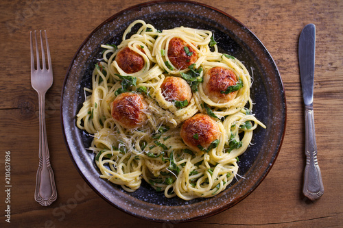 Pasta with meatballs and spinach. Spaghetti with meatballs in bowl on wooden table. overhead, horizontal