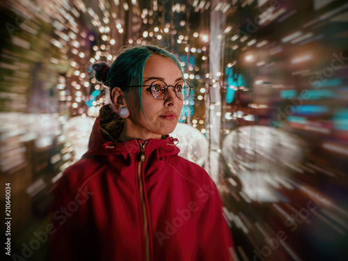 Young beautiful girl with blue dyed unusual hair, transparent glasses, piercing standing at night street with neon lights background. Portrait of happy cute stylish teenager.