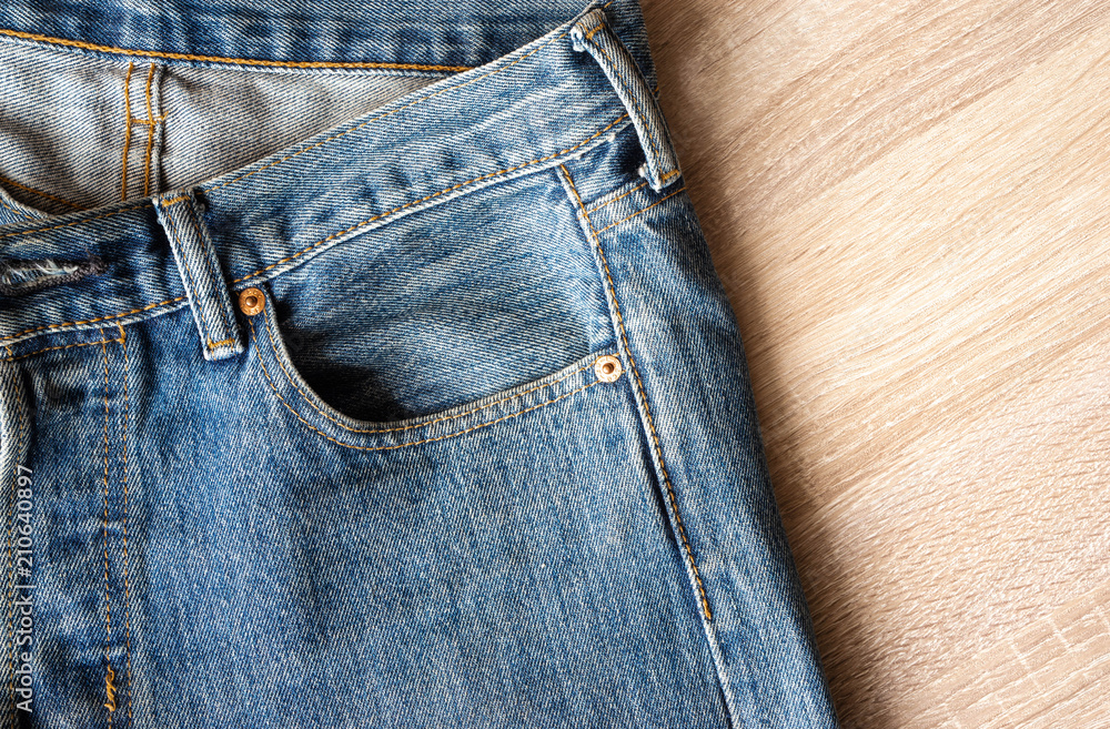 close up front blue jeans texture and details on wooden background close up front blue jeans texture and details on wooden background