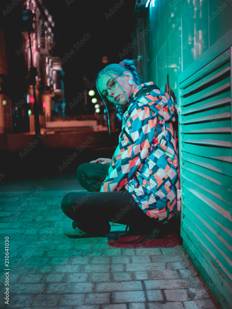 Φωτογραφία Young pretty girl with unusual hairstyle near glowing turquoise neon light of the city at night