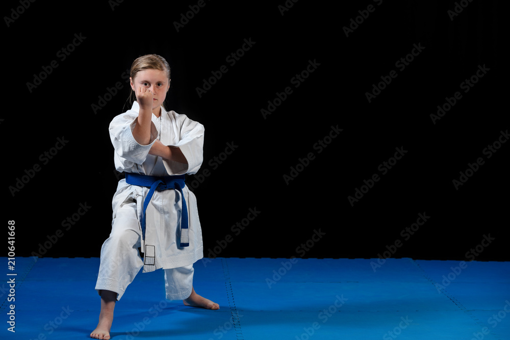 sweet little girl in martial arts practice like karate kid alone isolated on black background