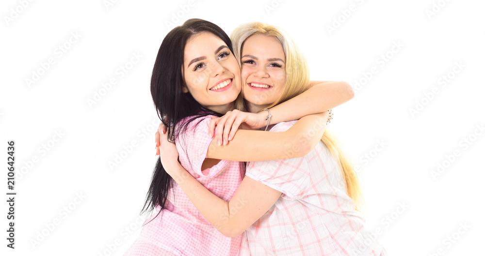 Two beautiful girls in pajama hugs. Best friends concept. Ladies on smiling faces hugs each other tight, white background, isolated. Two beautiful girls in pajama hugs. Best friends concept. Ladies on smiling faces hugs each other tight, white background, isolated.